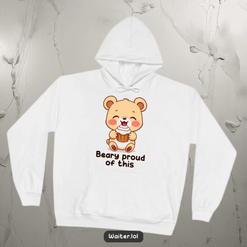 Funny bear cub hoodie with a delighted cartoon bear presenting a perfect cupcake with a beaming smile, soft and heartwarming clothing.